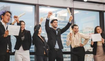 equipe bem-sucedida de jovens empresários de perspectiva no escritório, grupo de negócios de sucesso comemorando após a reunião com certificado falso foto