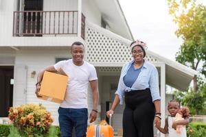 alegre família afro-americana com bagagem e caixas de transporte para nova casa, conceitos de família de felicidade foto