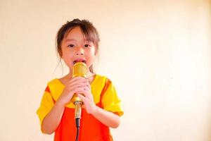 linda menina usa roupa amarelo-laranja gokowa ou mugunghwa, e segura música de canto de microfone de ouro. meninas e vestido de moda adolescente.