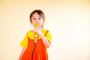 linda menina usa roupa amarelo-laranja gokowa ou mugunghwa, e segura música de canto de microfone de ouro. meninas e vestido de moda adolescente. foto