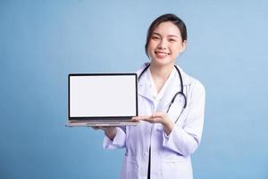 jovem médica asiática em pé sobre fundo azul foto