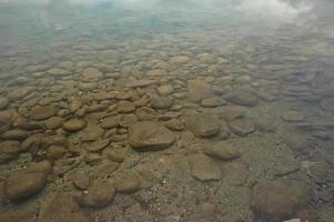 muitas pedras redondas sob lago claro foto