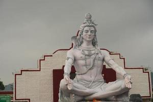 escultura de deus hindu shiva sentado em meditação no rio ganges em rishikesh, índia, foto