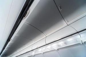 painel de controle do ar condicionado do avião sobre os assentos. ar abafado na cabine do avião com pessoas. nova companhia aérea de baixo custo foto