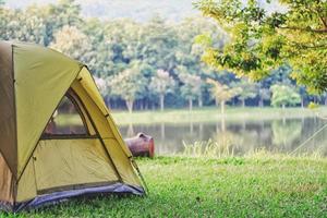 barraca verde de acampamento na floresta perto do lago foto