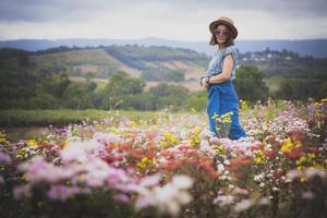 mulher de pé no jardim de flores desabrochando com clima relaxante foto