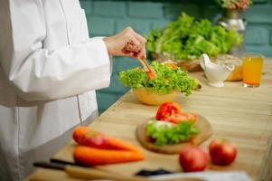 mão do chef, cozinhar salada de legumes, conceito de culinária saudável foto
