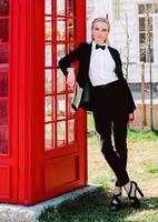 retrato de mulher loira bonita elegante em terno preto de homem perto de caixa de telefone vermelha foto