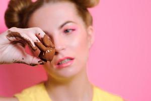 retrato de uma jovem loira atraente bonita com doces de chocolate nos dedos foto