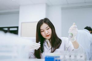 jovem cientista médico trabalhando em laboratório médico, jovem cientista usando pipeta automática para transferir amostra foto