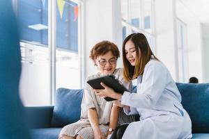 jovem médico consultando paciente sênior na clínica de saúde foto