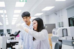 dois jovens cientistas médicos olhando para o tubo de ensaio no laboratório médico, selecione o foco no cientista masculino foto