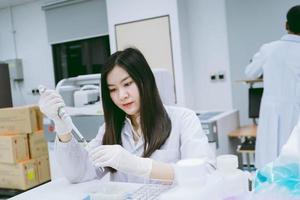 jovem cientista médico trabalhando em laboratório médico, jovem cientista usando pipeta automática para transferir amostra foto