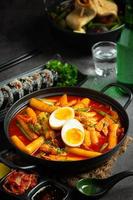 comida tradicional coreana de queijo tokbokki no fundo da placa preta. prato de almoço. foto