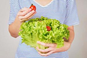 mulher segura buquê de alface com tomate cereja nas mãos. conceito de nutrição saudável foto