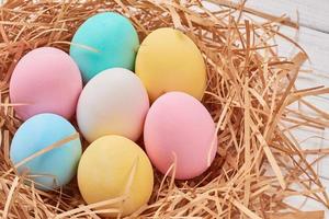 fundo de páscoa. ovos de páscoa coloridos no ninho de papel em um fundo branco, close-up