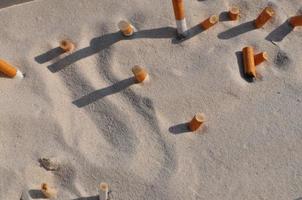 pontas de cigarro na areia foto