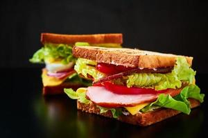 sanduíche caseiro com alface e presunto em um fundo preto, close-up foto