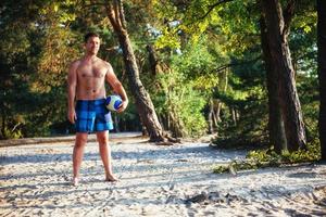 cara jovem jogando vôlei na praia foto