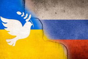 desfocar a imagem borrada bandeira da rússia e da ucrânia com um pombo de pássaro da paz branco pintado em uma parede de concreto. relação entre a Ucrânia e a Rússia. foto