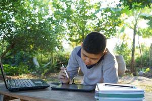 menino sentado online estudando com intenção. campo de educação on-line de conceito foto