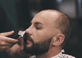 homem barbudo cortando o cabelo da barba foto