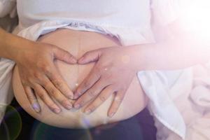 a futura mãe coloca as mãos na barriga para se comunicar com o feto e espera o dia em que o bebê nasce. conceito de comunicação da mãe grávida para o feto. foto