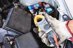 mecânico de automóveis trabalhando na garagem de mecânica, técnico verificando fusível e relé no motor do carro, serviço de reparo e manutenção foto