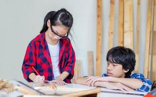 crianças aprendendo marcenaria na oficina de artesão, menino adolescente com sua irmãzinha construindo uma oficina juntos em uma oficina de carpintaria. foto