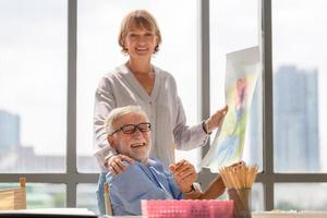 retrato de casal sênior feliz pintando em uma tela na sala de estar, homem mais velho e mulher desenhando juntos em uma tela, conceitos de aposentadoria feliz foto