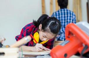 crianças aprendendo marcenaria na oficina de artesão, menino adolescente com sua irmãzinha construindo uma oficina juntos em uma oficina de carpintaria. foto