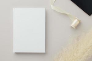 maquete de capa em branco de livro branco em um fundo bege com flor seca, postura plana, maquete
