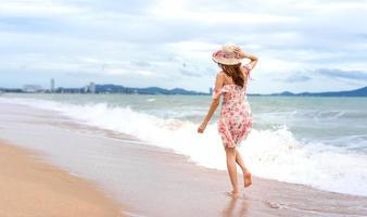 jovem asiática caminhar e relaxar na praia foto