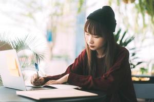 mulher jovem estudante universitário asiático adulto com laptop para estudar no café em dia de inverno. foto