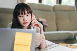 mulher adolescente asiática trabalha e estuda on-line via internet em casa. foto