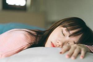 jovem asiática bonita adolescente dorme no quarto de manhã foto