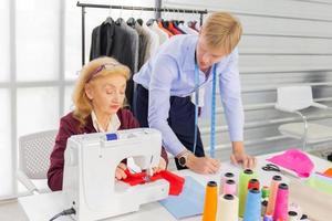 designers de trabalho em equipe profissional, homens jovens e mulheres idosas no escritório com uma variedade de tons de tecido e equipamentos para vários projetos. foto