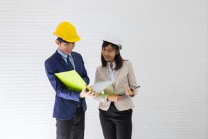 dois capatazes asiáticos masculinos e femininos usando um capacete e de pé e conversando no local do evento foto