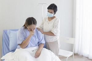 uma mãe asiática cuida de sua filha doente em uma cama de hospital. foto