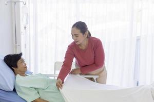 uma mulher asiática cuida de sua mãe doente na cama em um hospital. foto