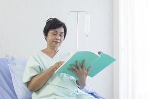 as idosas asiáticas sentaram-se na cama para ler no hospital. foto