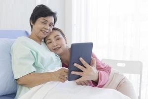 a mãe doente estava deitada na cama do hospital e sua filha uma ao lado da outra estava fazendo videochamadas de maneira feliz. foto