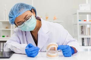 dentista feminina asiática está introduzindo conhecimento com equipamentos de prótese em clínicas odontológicas.
