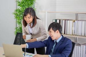 uma colega de trabalho asiática estava conversando com um homem de negócios na mesa na mão segurando uma xícara de café. foto