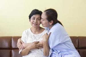 a filha asiática, que estava doente no hospital, abraçou e cheirou as bochechas de sua mãe, que cuidava alegremente. foto