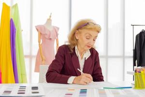 designers femininas profissionais estão desenhando esboços em papel no escritório de uma loja de costura. foto