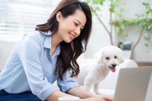 jovem empresária asiática trabalhando em casa com seu cachorro foto