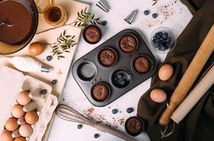 cupcakes com creme e mirtilos na mesa da cozinha foto