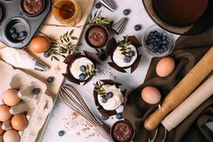 cupcakes com creme e mirtilos na mesa da cozinha foto