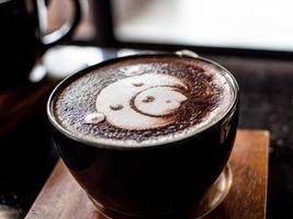 xícara de café com leite e cara de urso bolha aet na mesa de madeira foto